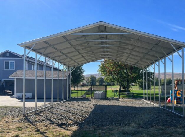 A spacious A-framed carport in Abilene TX, featuring a metal structure and open sides, set in a grassy area.