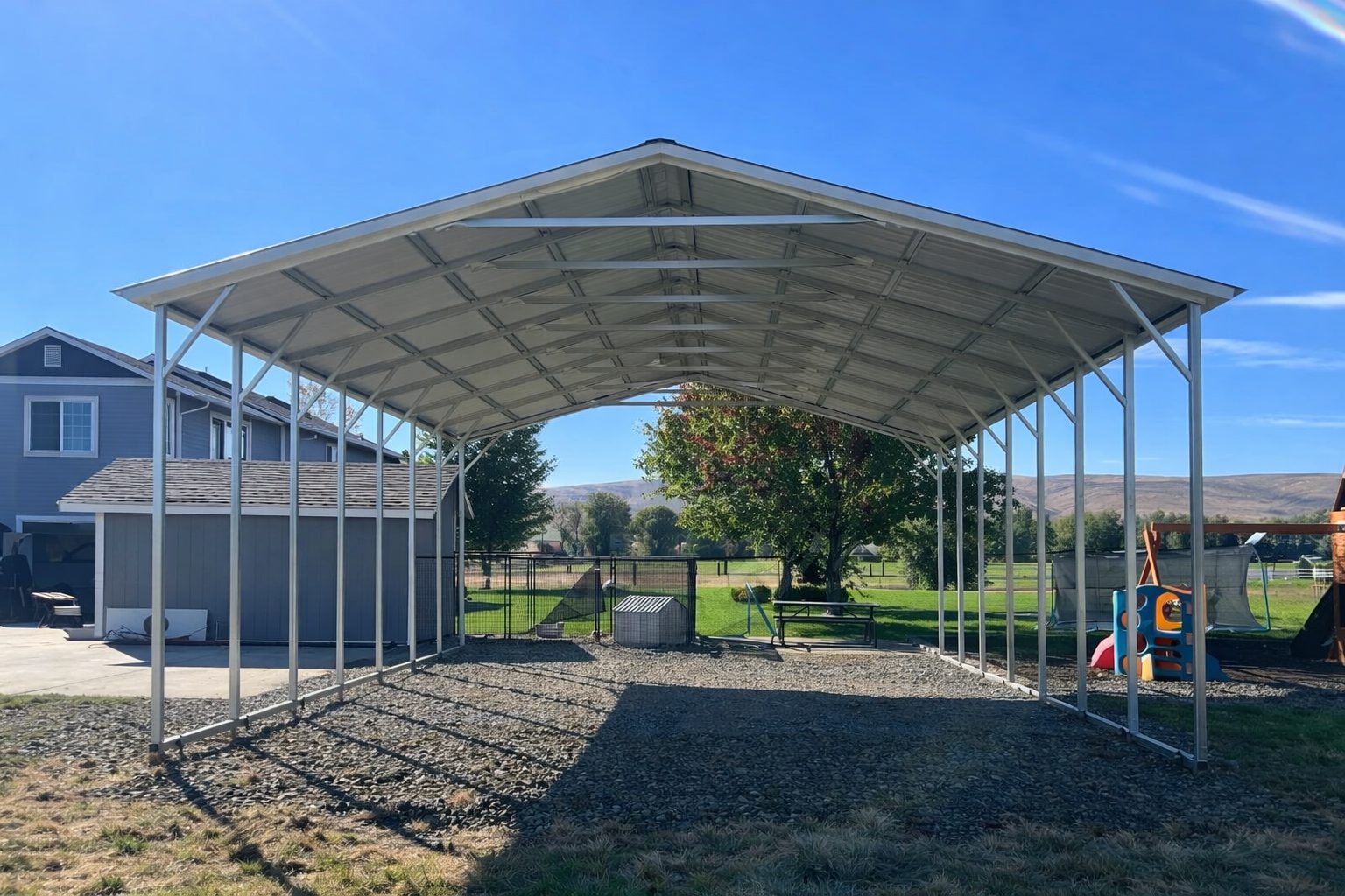 A spacious A-framed carport in Abilene TX, featuring a metal structure and open sides, set in a grassy area.