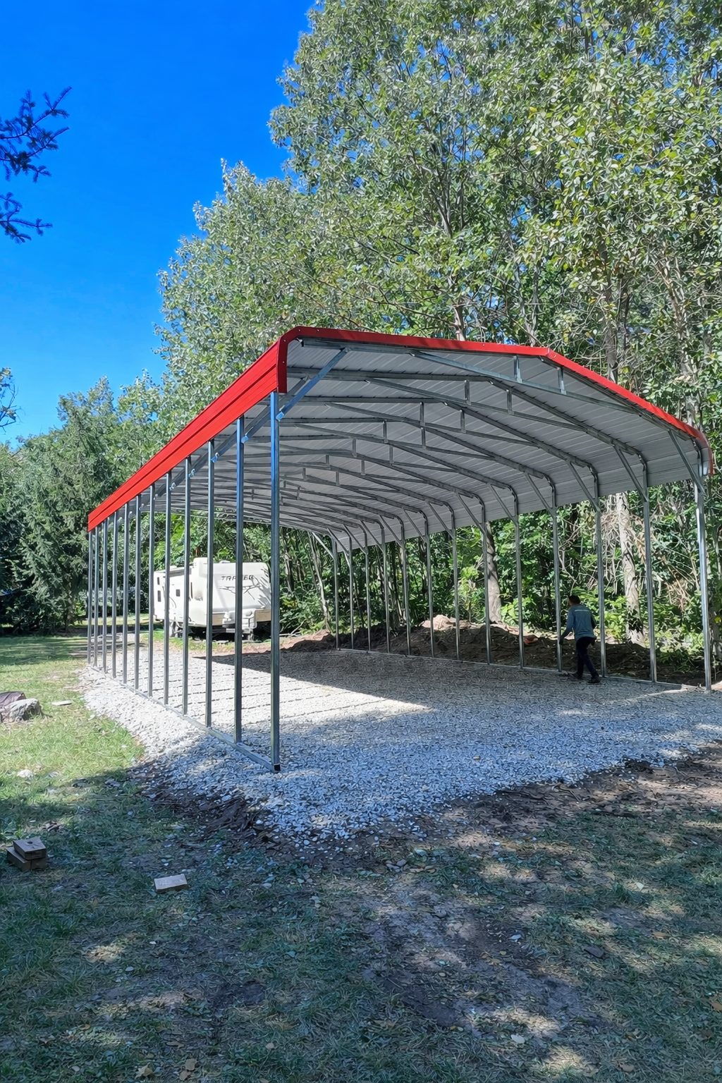 Standard framed carport with a red roof, set on gravel, surrounded by trees in Ashland, KY.