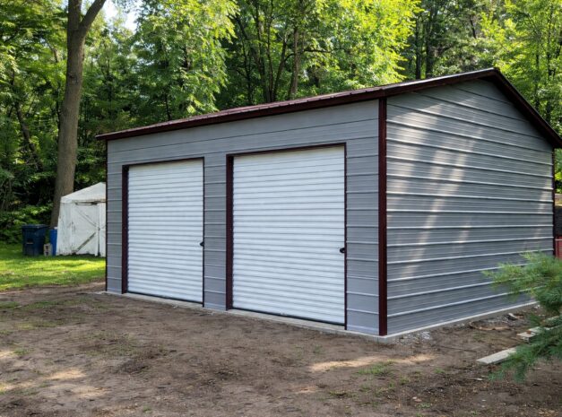 Standard shed in Brownfield, TX, featuring two roll-up doors and a gray exterior surrounded by trees.