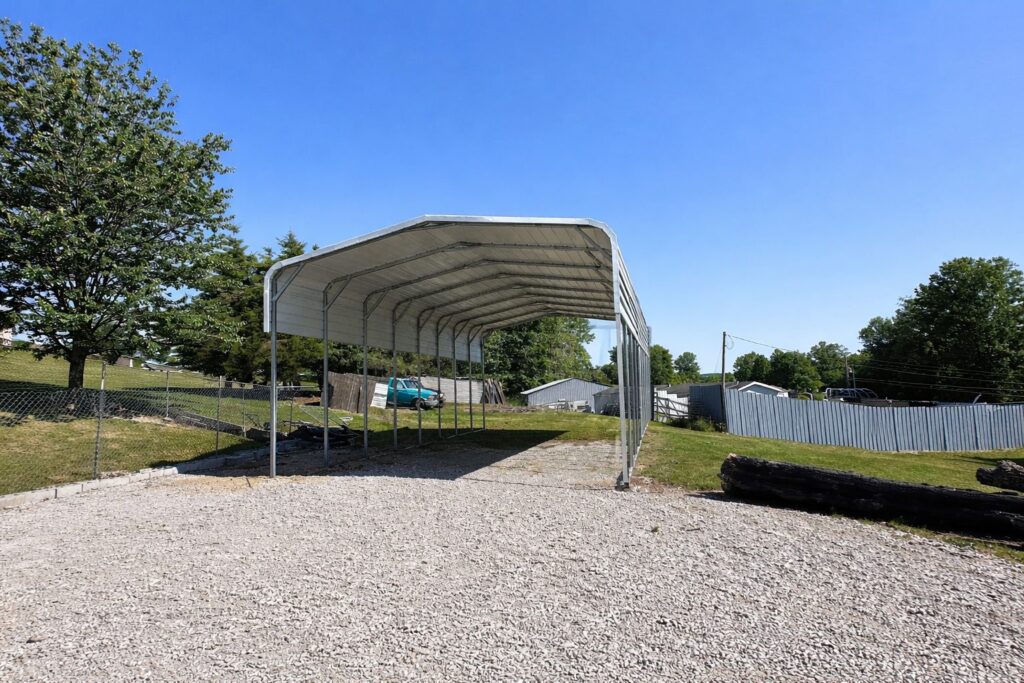 Standard framed carport in Buckeye AZ, showcasing a spacious design with a gravel base and clear blue sky.
