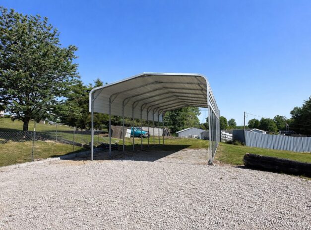 Standard framed carport in Buckeye AZ, showcasing a spacious design with a gravel base and clear blue sky.