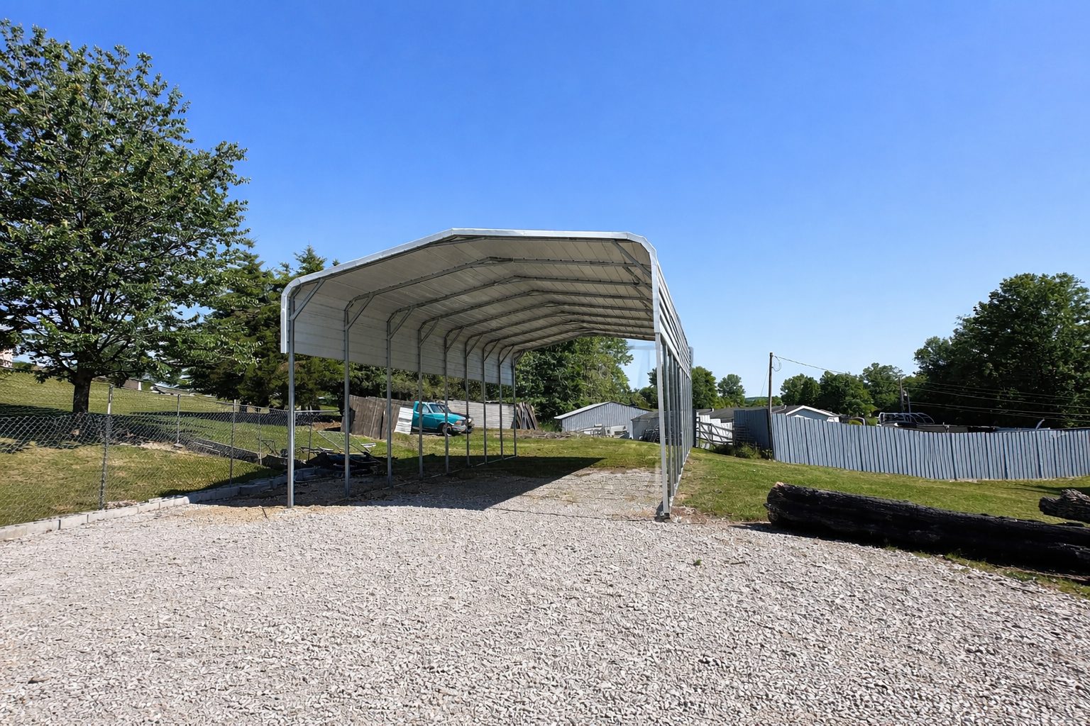 Standard framed carport in Buckeye AZ, showcasing a spacious design with a gravel base and clear blue sky.