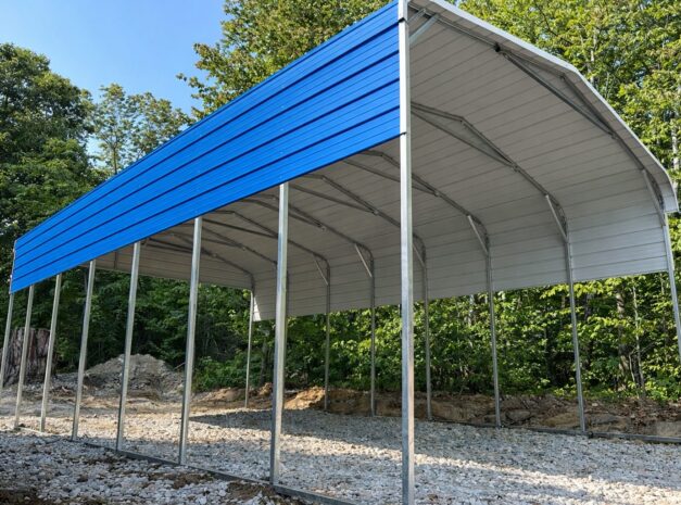 Standard framed carport with a blue roof, set on a gravel base surrounded by trees, ideal for Bullhead City AZ.