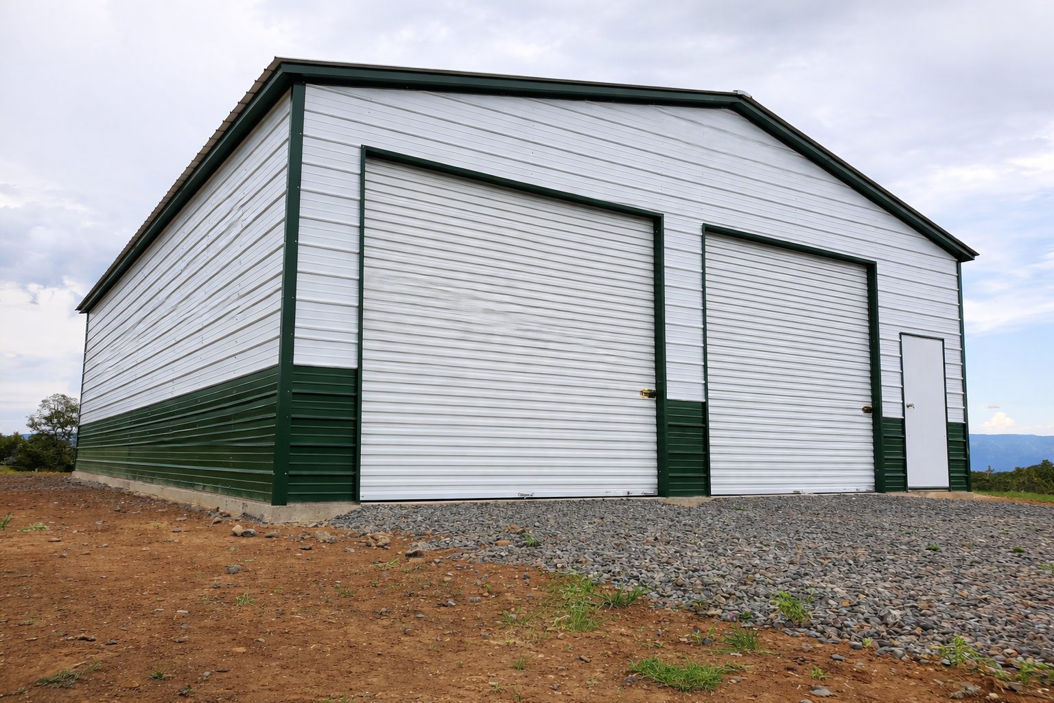 Expansive garage in Cadillac MI with green and white siding, featuring large roll-up doors and a side entrance.