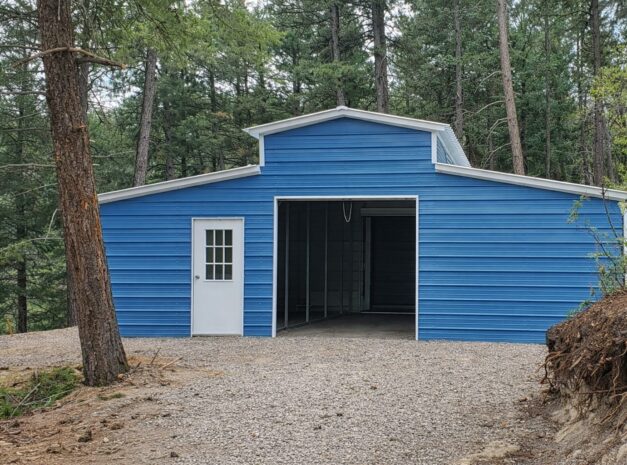 A blue traditional barn with a white door, surrounded by trees and gravel, showcasing available color options.