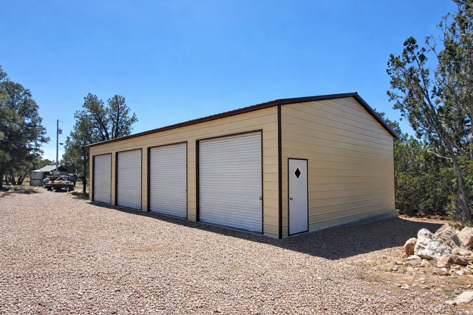 Expansive garage with multiple roll-up doors, showcasing a durable steel structure in a natural setting.