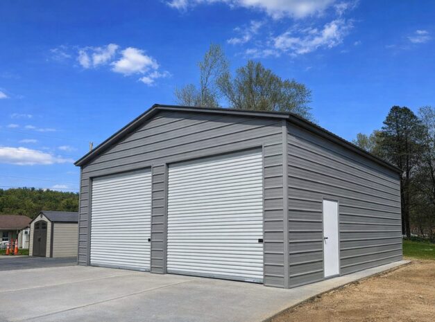 Standard garage in Creston, IA, featuring a gray exterior and large roll-up doors against a clear blue sky.