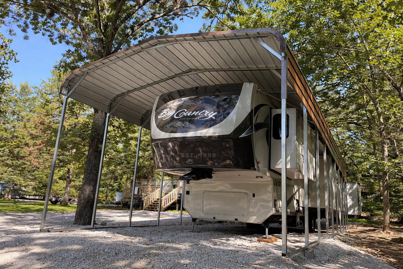 Standard framed carport sheltering an RV in a wooded area, showcasing durable construction and design.