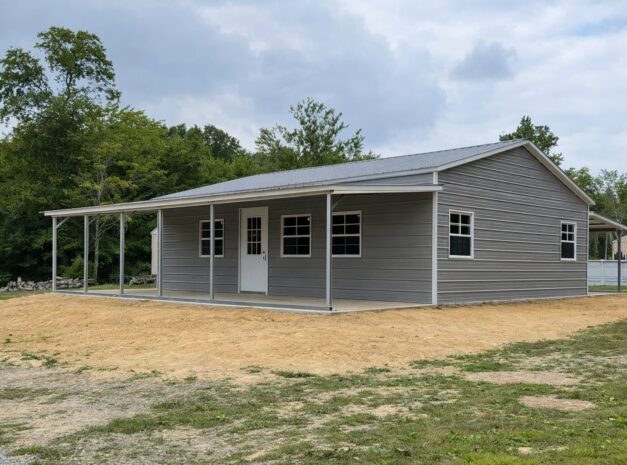 Gray utility shed with a porch, featuring multiple windows, set in a grassy area near trees in Fort Wayne, IN.