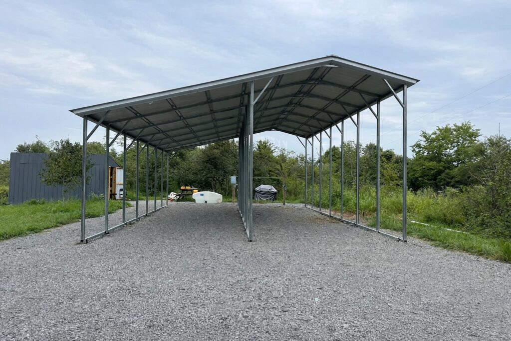 Custom RV carport with a metal frame, set on gravel, surrounded by greenery in Grand Rapids, MI.