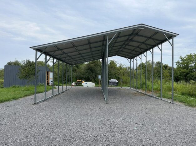 Custom RV carport with a metal frame, set on gravel, surrounded by greenery in Grand Rapids, MI.