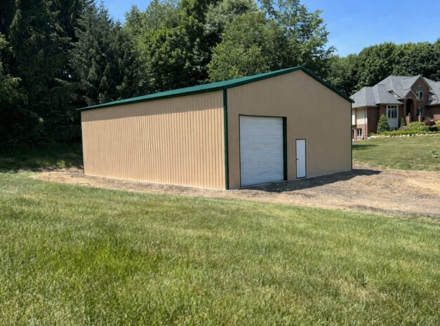 Clear span steel building in Grandview, TX, featuring a beige exterior and green roof, set in a grassy area.