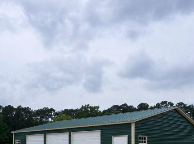 Expansive green garage with three white doors and a side entrance, showcasing Legacy Steel Structures design.