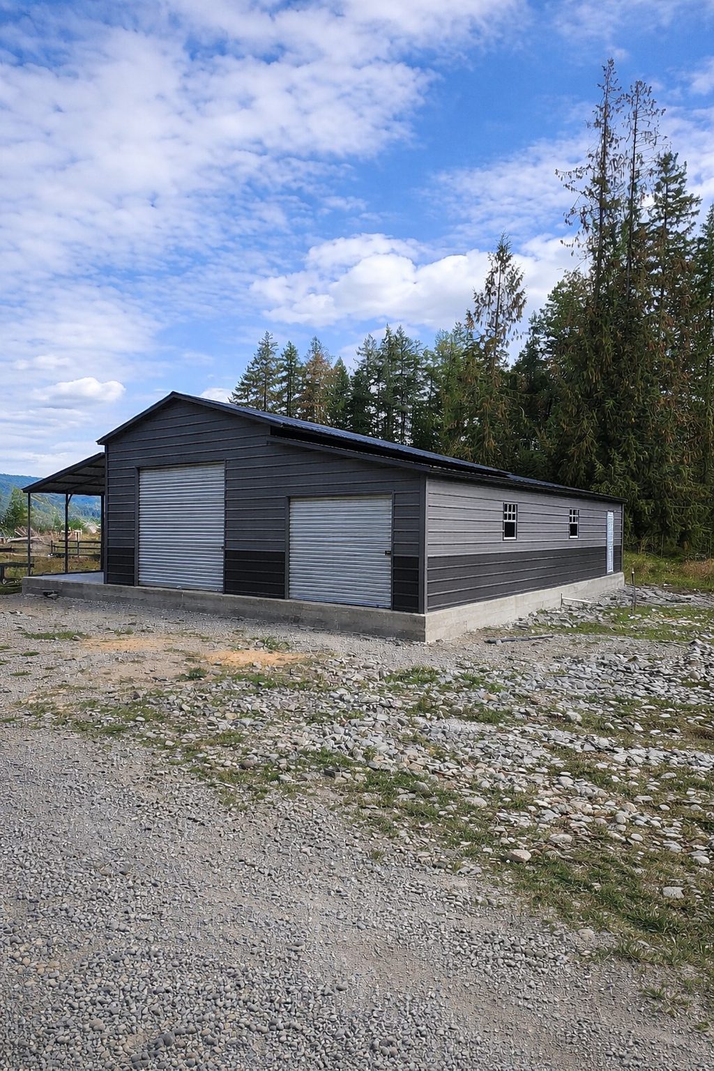 Custom barn structure in Lorain, OH, featuring a gray exterior and roll-up doors, set against a scenic landscape.