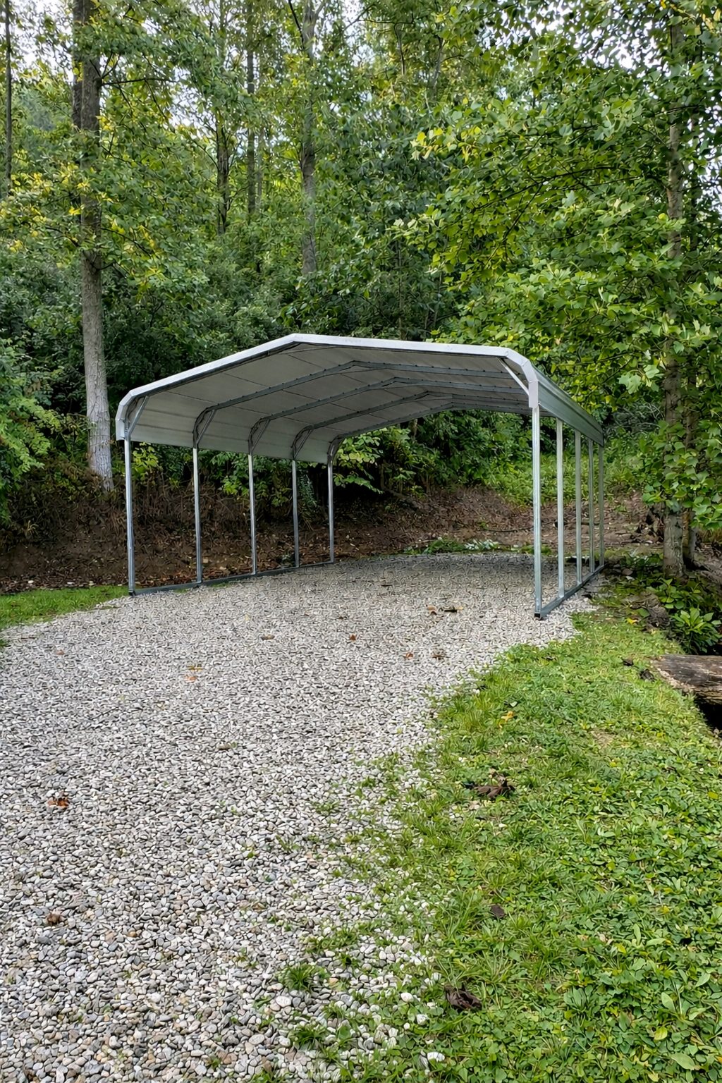 Standard carport in a gravel area surrounded by trees, showcasing durable steel construction.