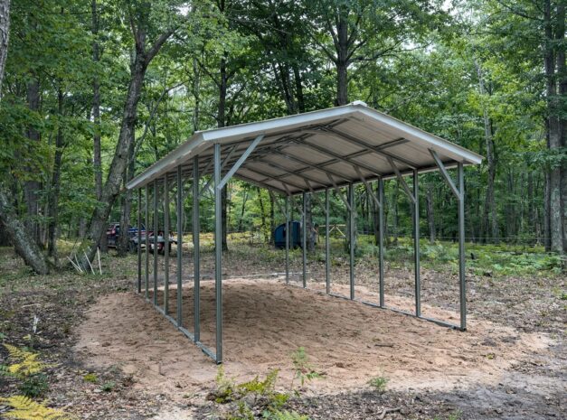 A-frame carport structure set in a wooded area, showcasing its steel frame and open design.