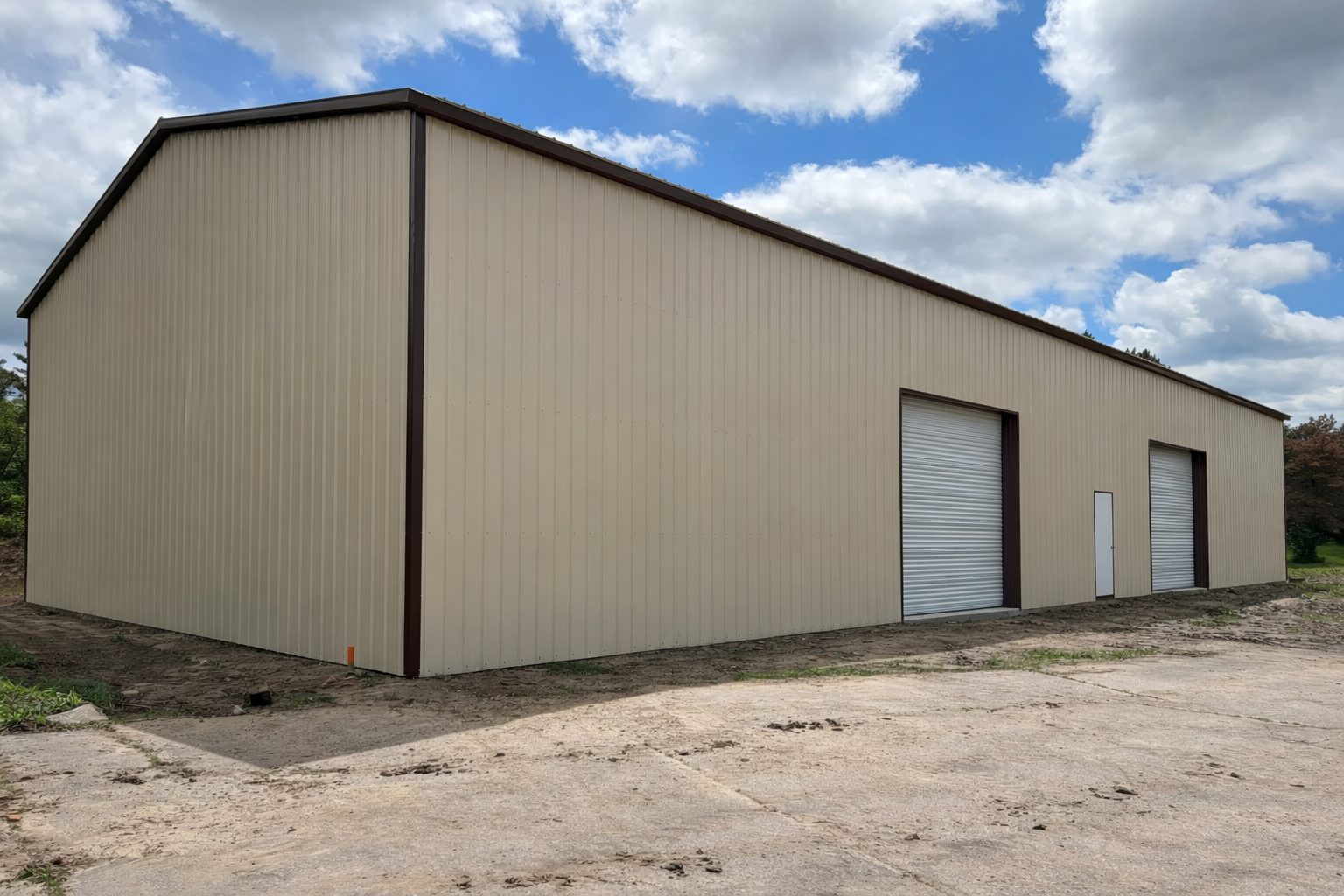 A large beige steel building with roll-up doors, showcasing the Grand Span design in Springtown, TX.