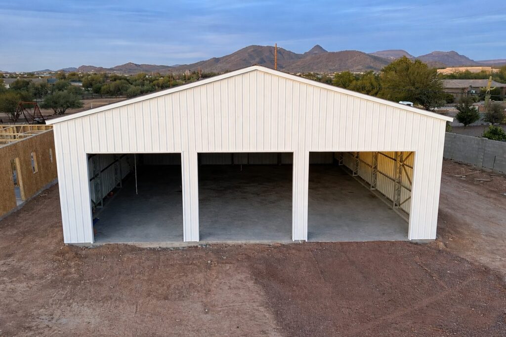 Large white steel building with open bays, set against a mountainous landscape in Sunset, TX.