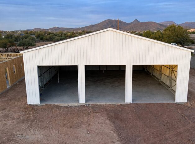 Large white steel building with open bays, set against a mountainous landscape in Sunset, TX.