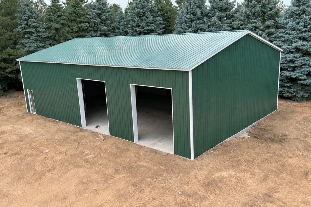 A green steel building with open doors, surrounded by trees, showcasing a Grand Span design in Tarrant County, TX.