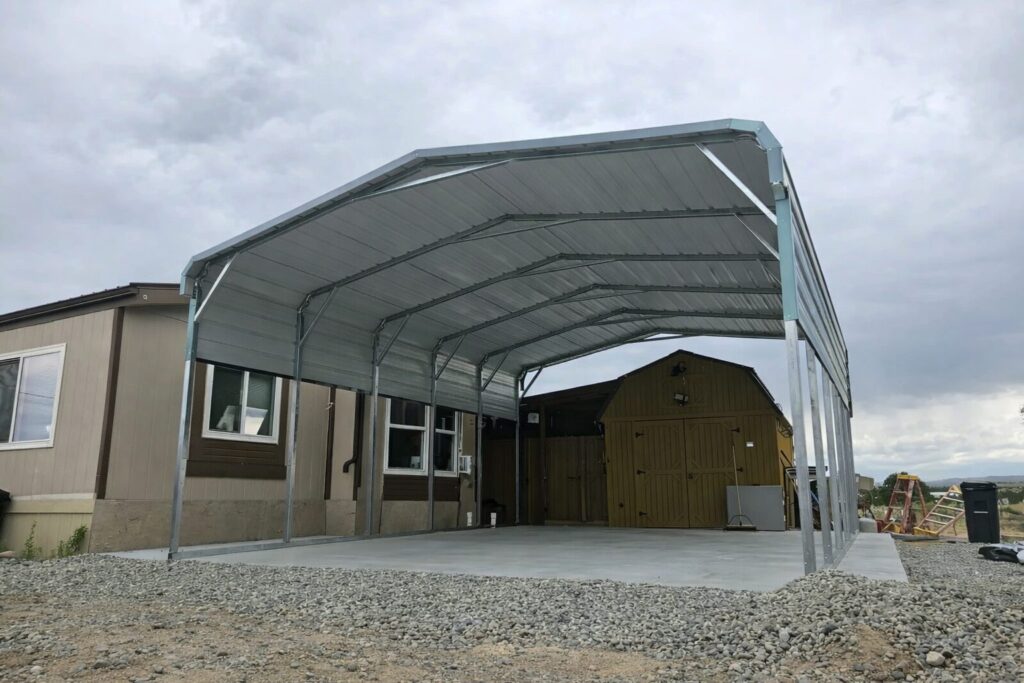Standard framed carport in Tyler, TX, featuring a metal structure with a concrete base and nearby buildings.